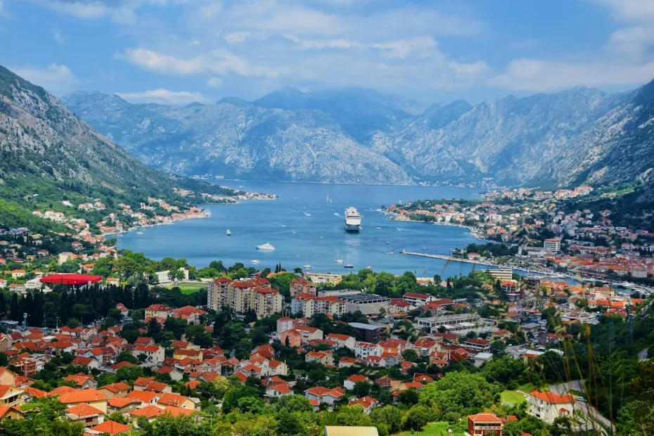 La baie de Kotor vue d'en haut, montagnes plongeant dans l'eau immobile et vieille ville fortifiée au bord de l'Adriatique.