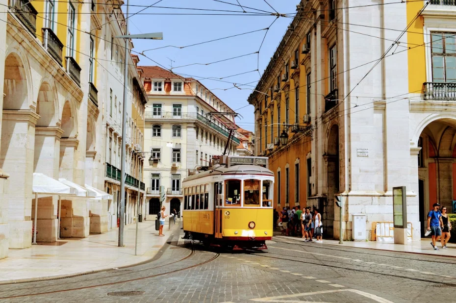 Tramway jaune dans une rue en pente de Lisbonne, façades en azulejos